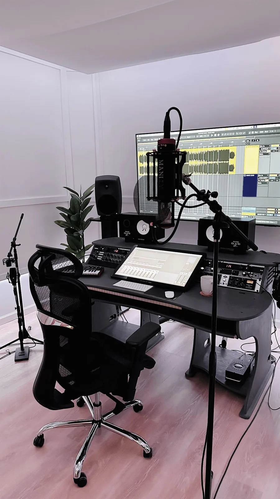 The Nuve control room — desk, monitors, outboard rack, a Manley microphone and a session open on the wall screen.